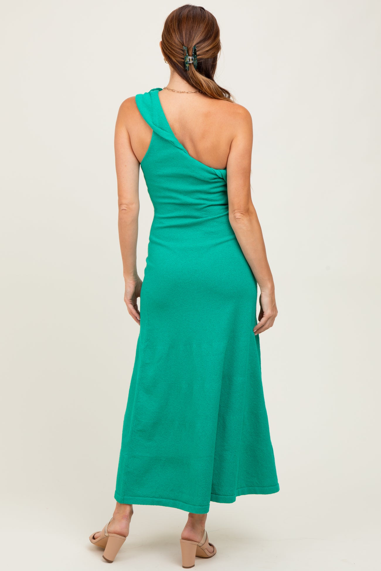 woman wearing a green one-shoulder maxi dress, showing the back view