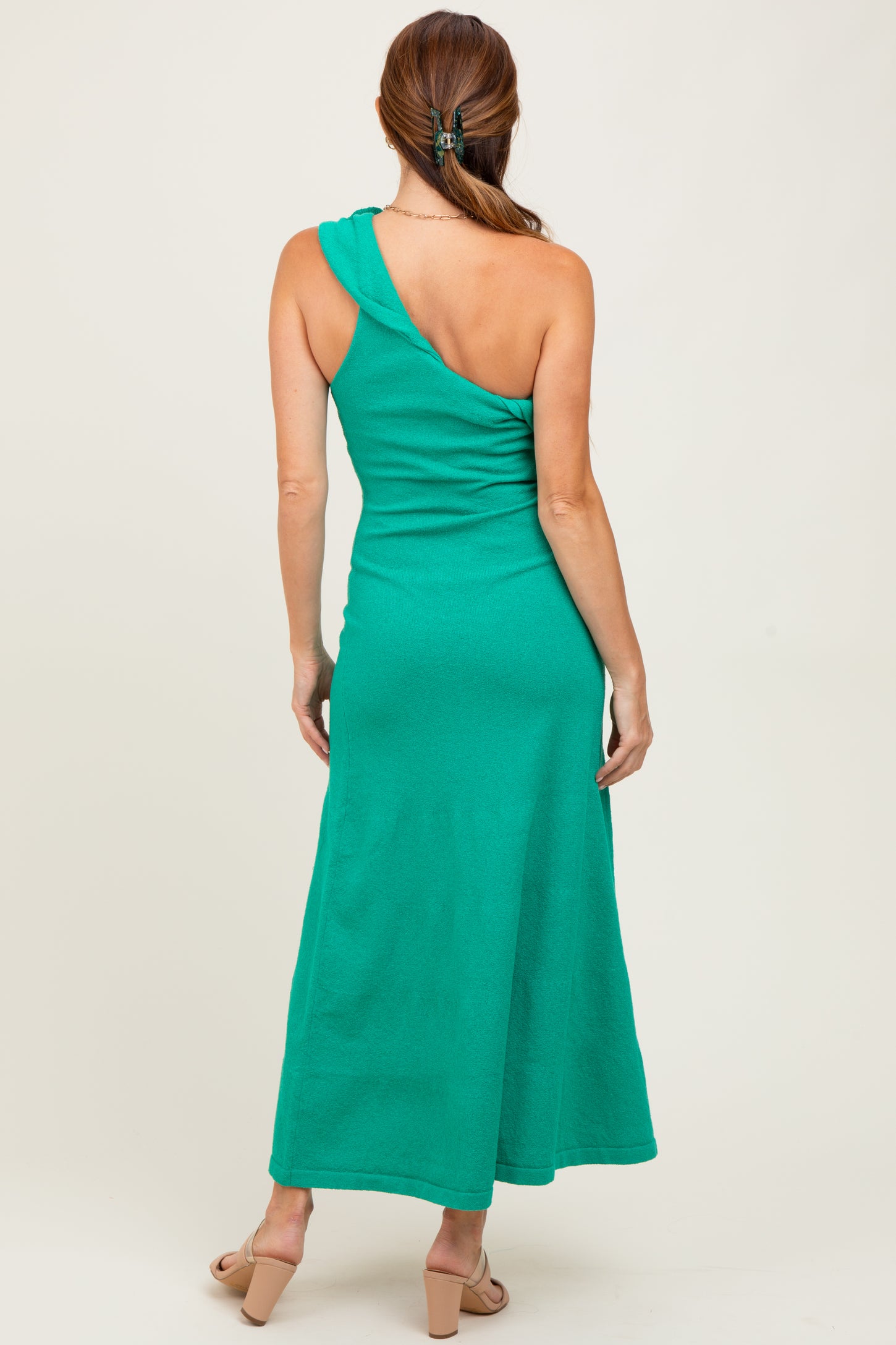 woman wearing a green one-shoulder maxi dress, showing the back view