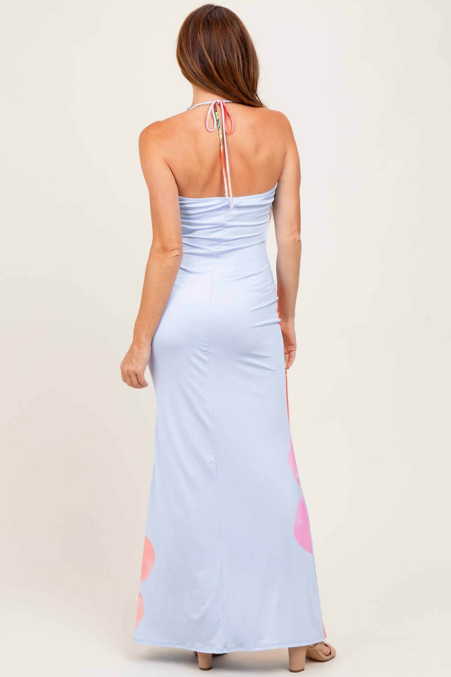 woman wearing a light blue halter neck maxi dress with pink floral accents on the hem