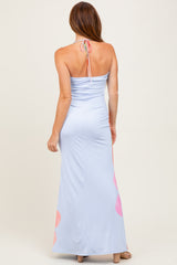 woman wearing a light blue halter neck maxi dress with pink floral accents on the hem