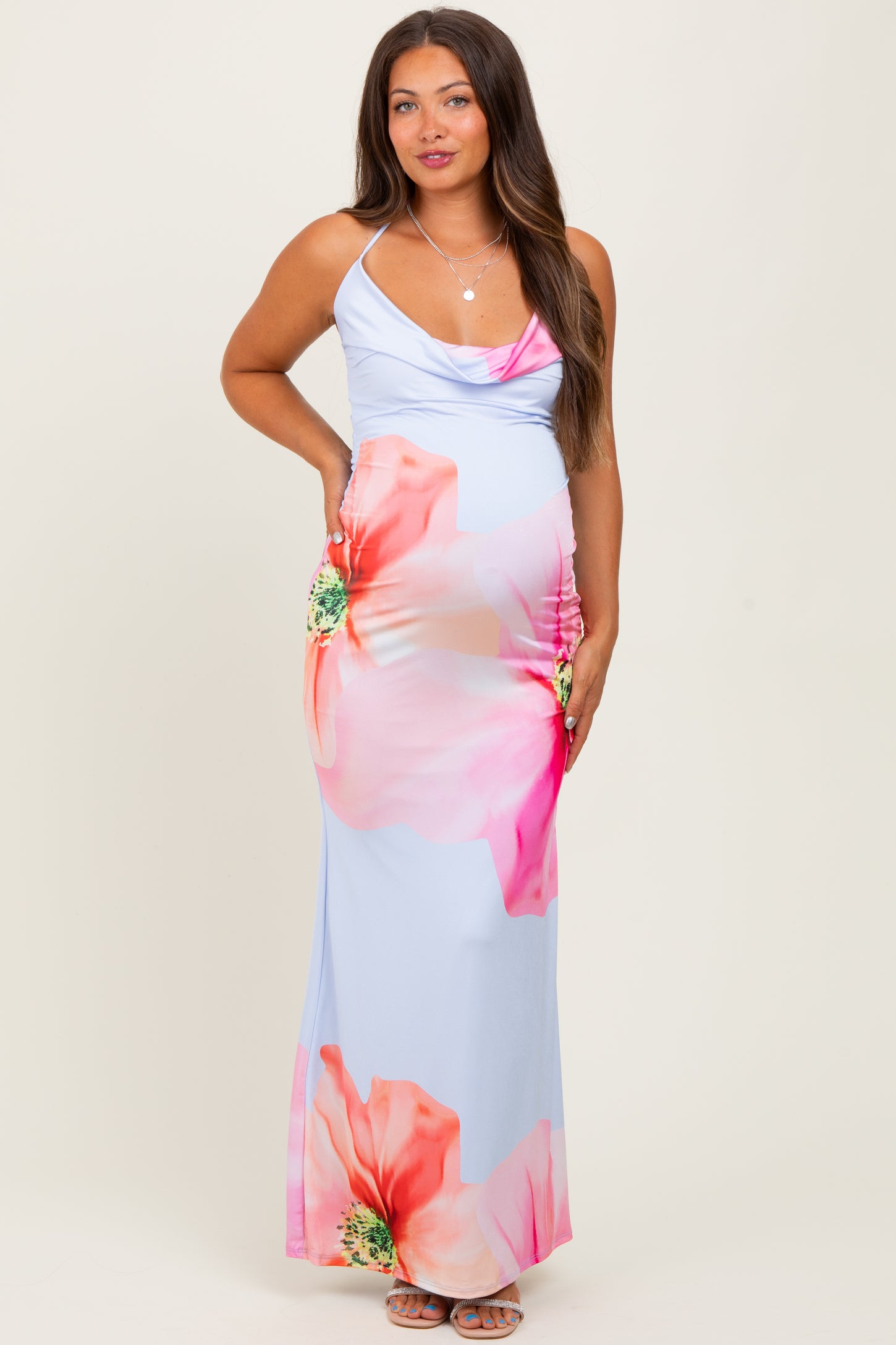 woman wearing a light blue maternity maxi dress with a floral print and ruched sides, showcasing her baby bump