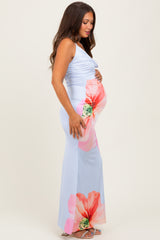 woman wearing a light blue maternity dress with pink floral design and holding her baby bump