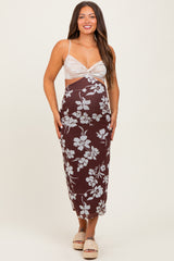 woman wearing a brown floral maternity dress with a fitted silhouette and thin straps, standing confidently
