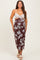 woman wearing a brown floral maternity dress with a fitted silhouette and thin straps, standing confidently