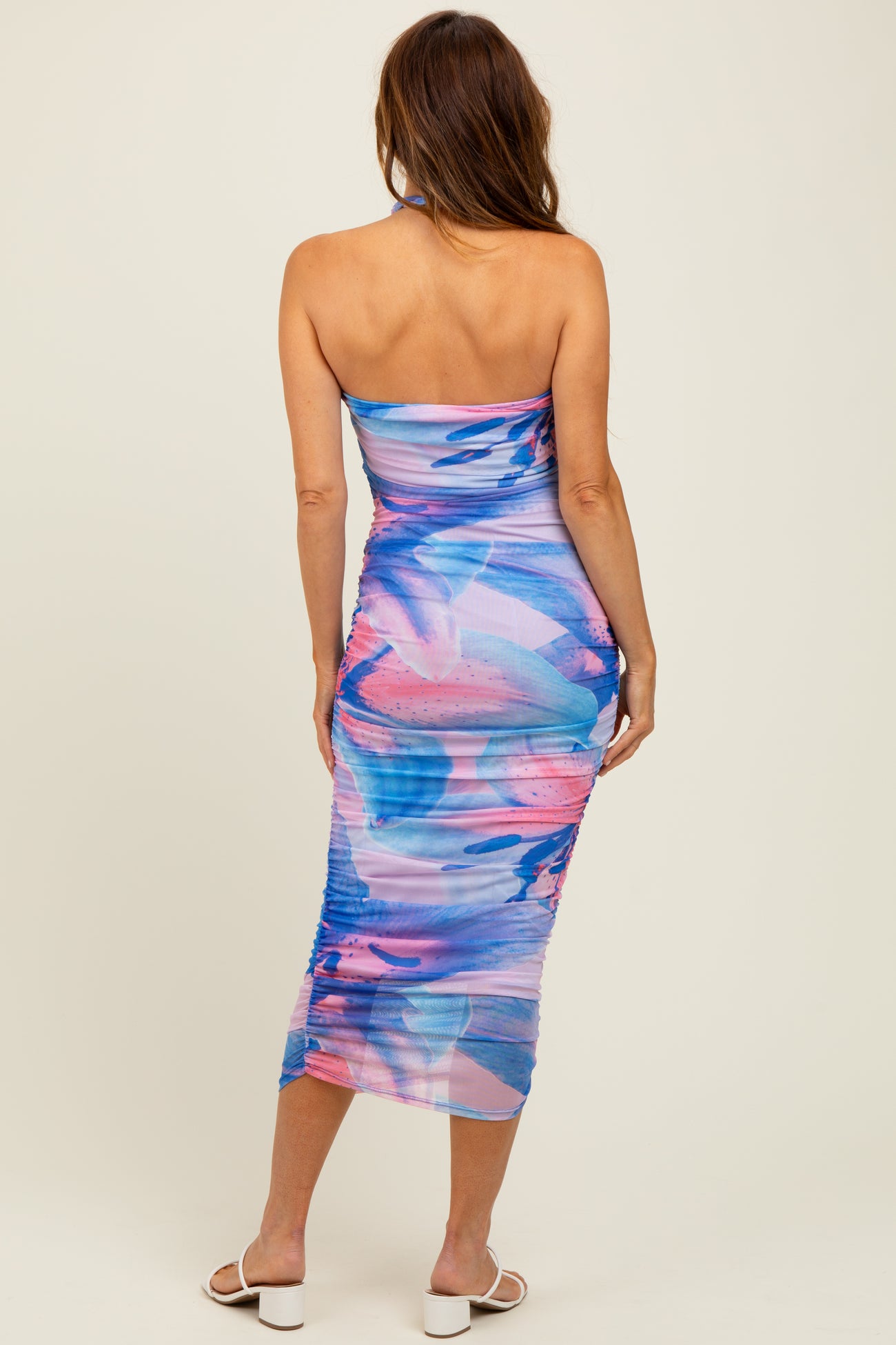 woman wearing a strapless midi dress with a colorful blue and pink abstract print and ruching details