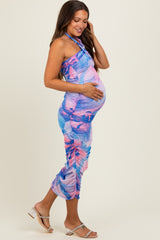 woman wearing a multicolored halter neck maternity dress and holding her baby bump