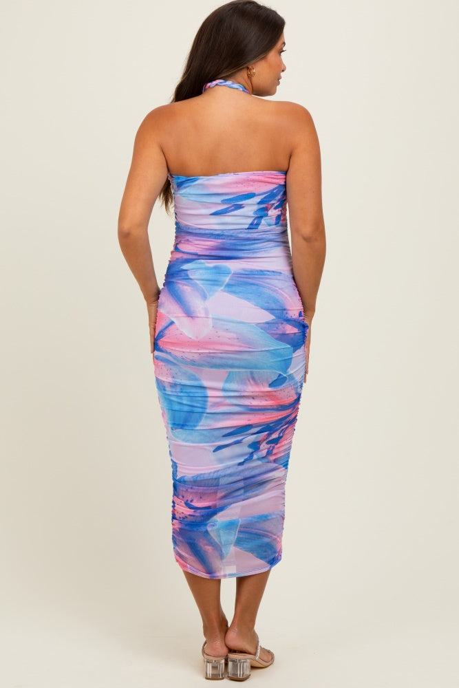 woman wearing a colorful halter neck maternity dress with a fitted silhouette and floral print, showcasing her baby bump from the back