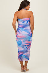 woman wearing a colorful halter neck maternity dress with a fitted silhouette and floral print, showcasing her baby bump from the back