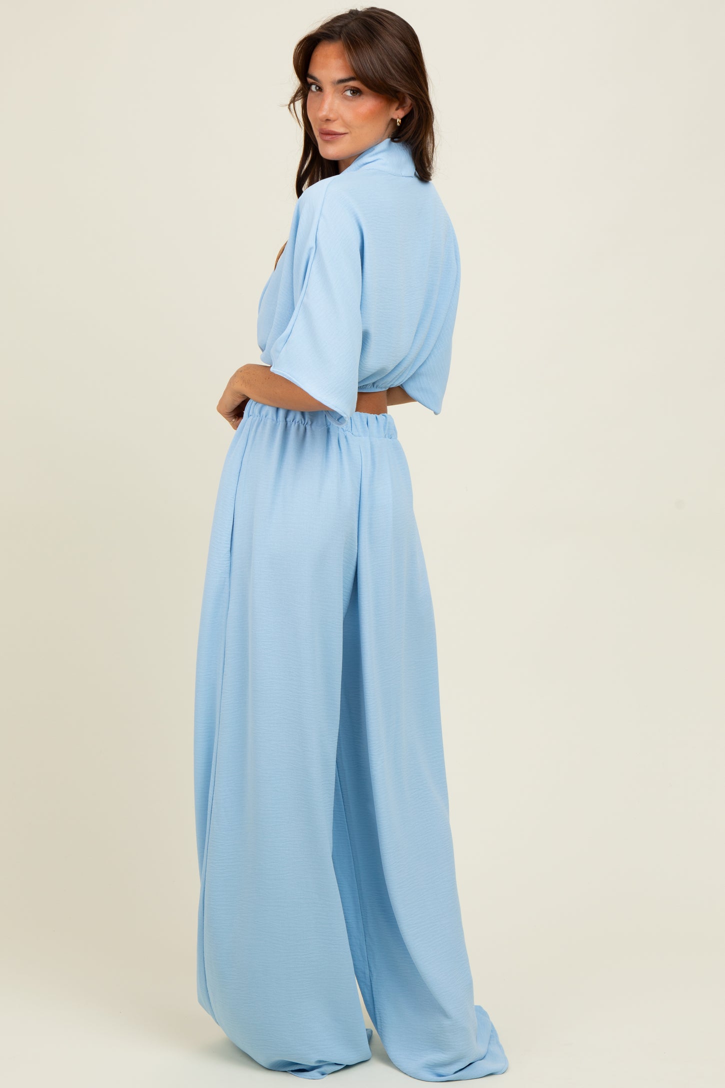 woman wearing a light blue two-piece outfit with a short-sleeve top and wide-leg pants, showing the back view
