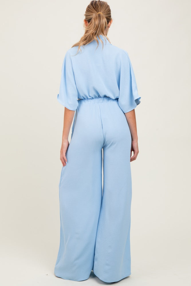 woman wearing a light blue maternity jumpsuit with wide legs and a relaxed fit, showing the back view