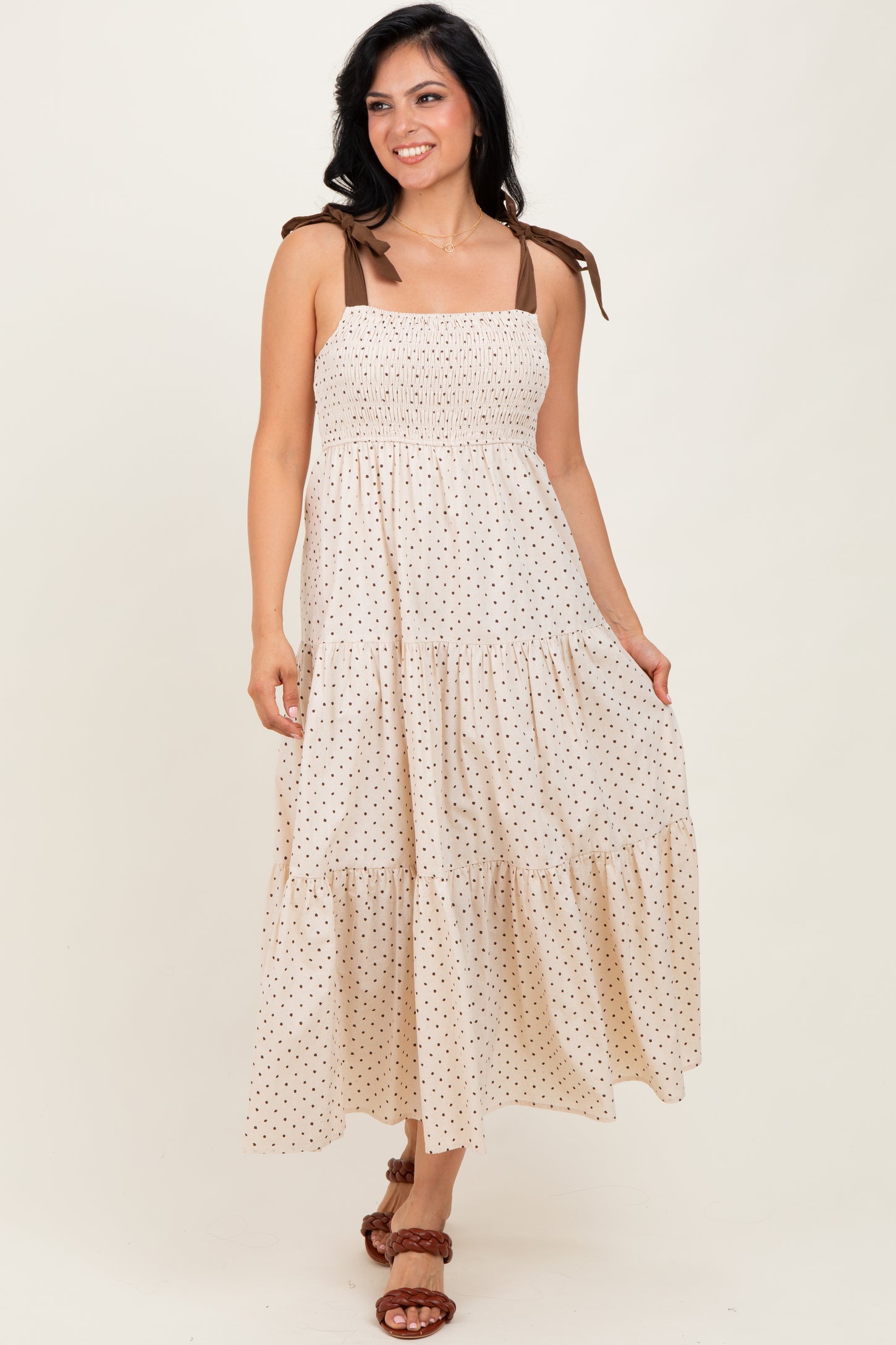woman wearing a cream and brown polka dot maxi dress with smocked bodice and adjustable straps