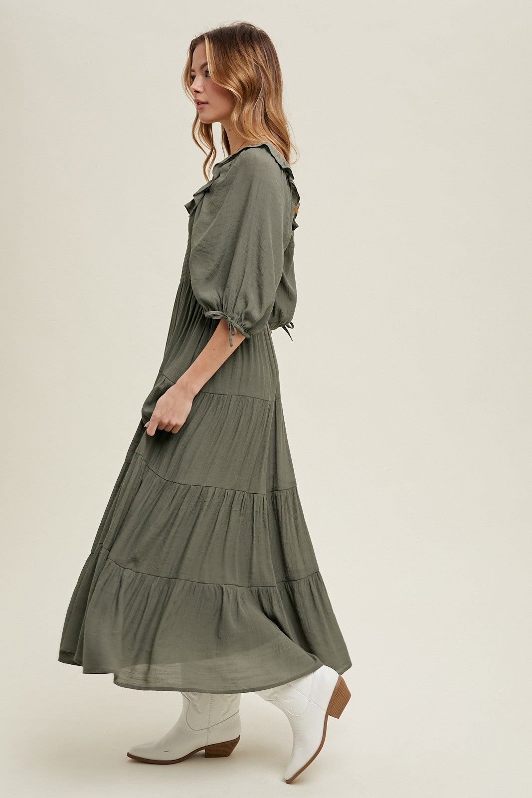 woman wearing a long olive green tiered maxi dress with puff sleeves and white ankle boots