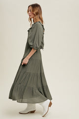 woman wearing a long olive green tiered maxi dress with puff sleeves and white ankle boots