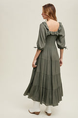woman wearing an olive green tiered maxi dress with puff sleeves and a smocked back detail