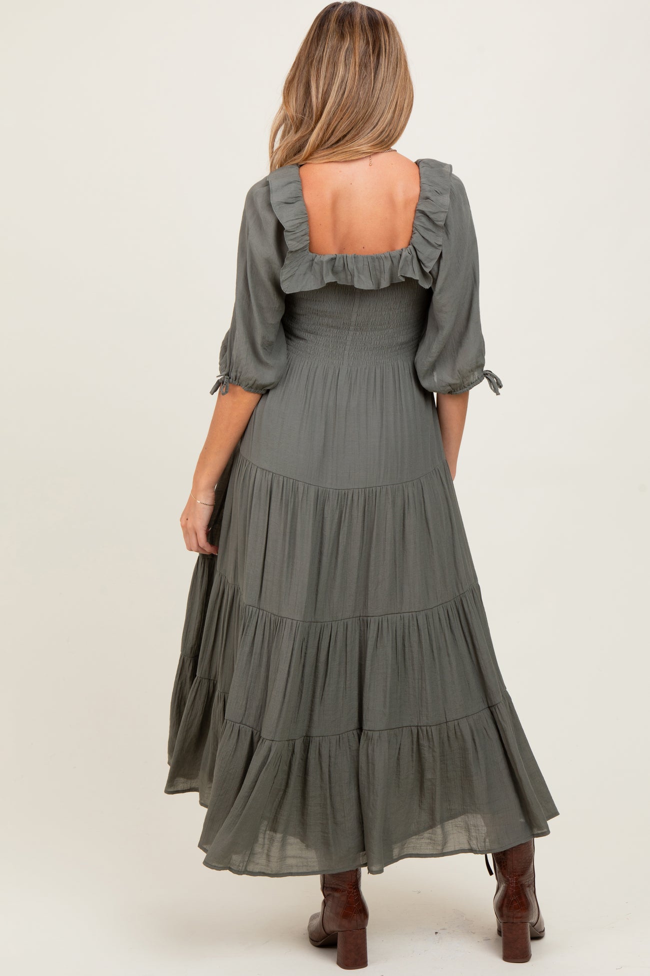 woman wearing a dark green ruffled back tiered maxi maternity dress with three-quarter sleeves