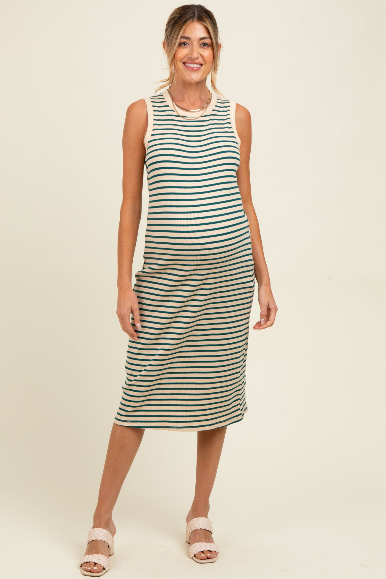 woman wearing a striped maternity midi dress with a fitted silhouette and a round neckline, showcasing her baby bump