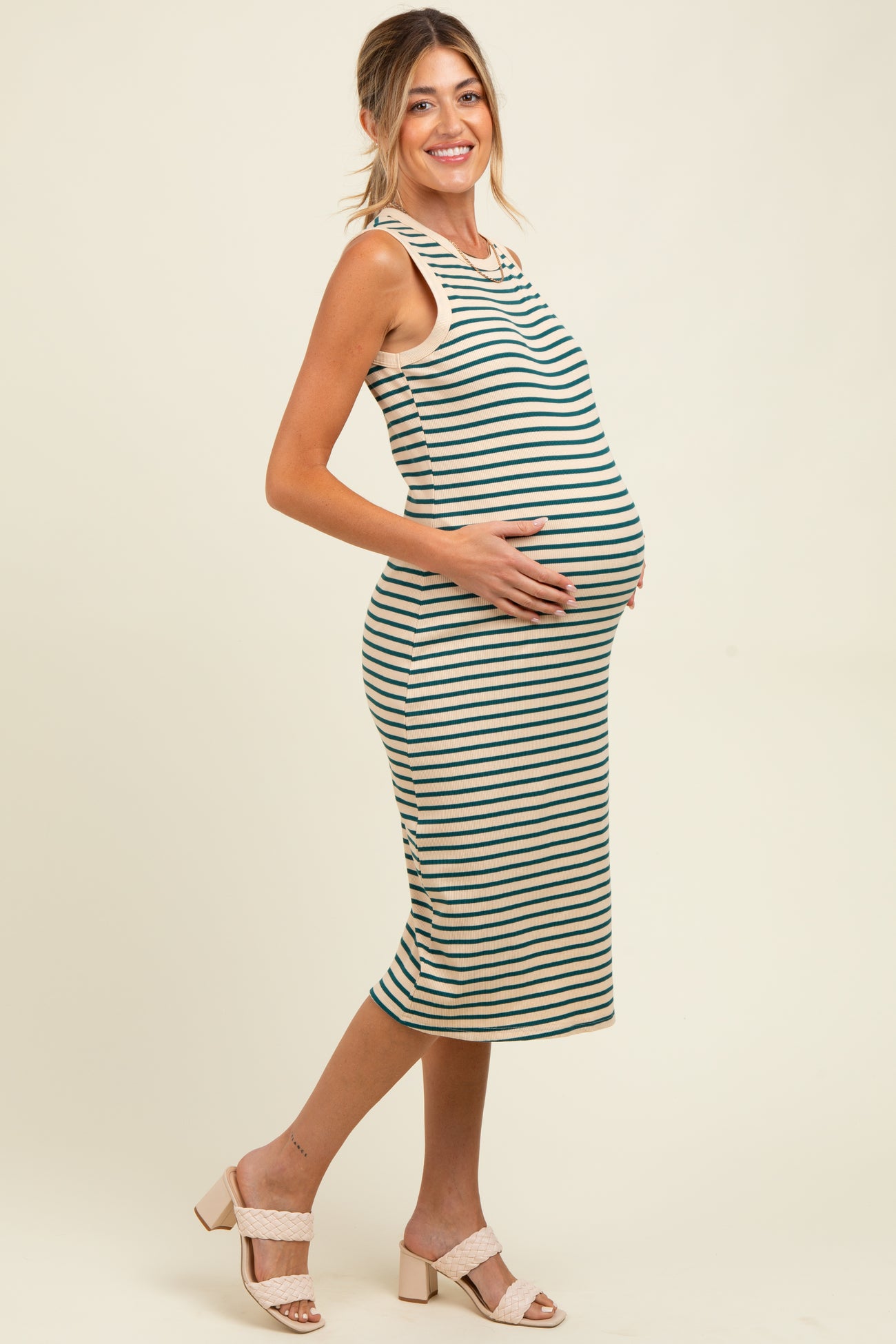 woman wearing a striped maternity dress, showing her baby bump, with a fitted silhouette and sleeveless design