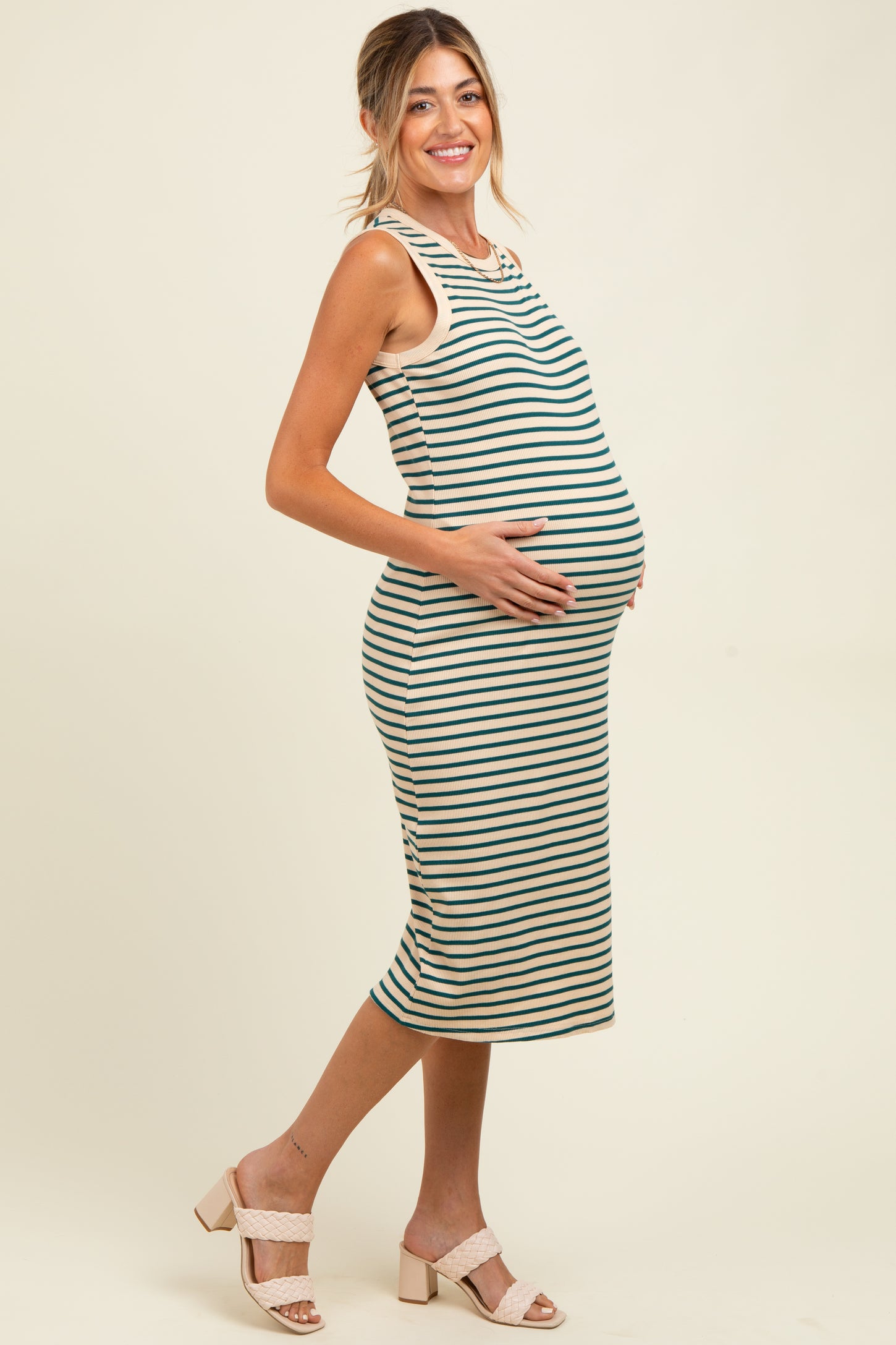 woman wearing a striped maternity dress, showing her baby bump, with a fitted silhouette and sleeveless design