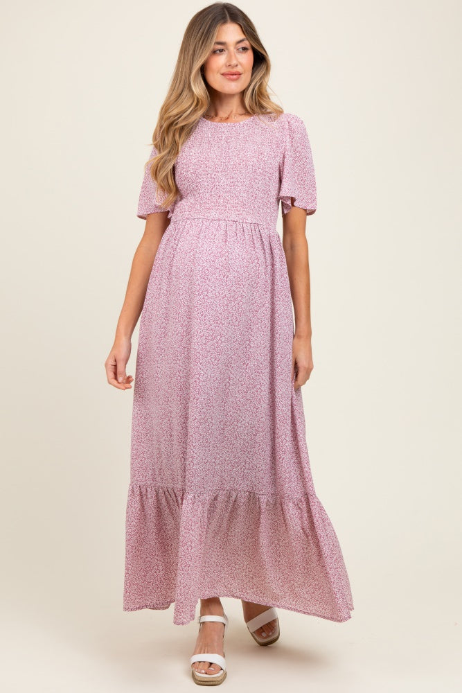 woman wearing a pink floral maternity maxi dress with short puff sleeves and a tiered skirt, baby bump visible