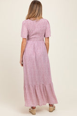 woman in a long pink floral maternity dress with puff sleeves and a tiered skirt, showing the back view