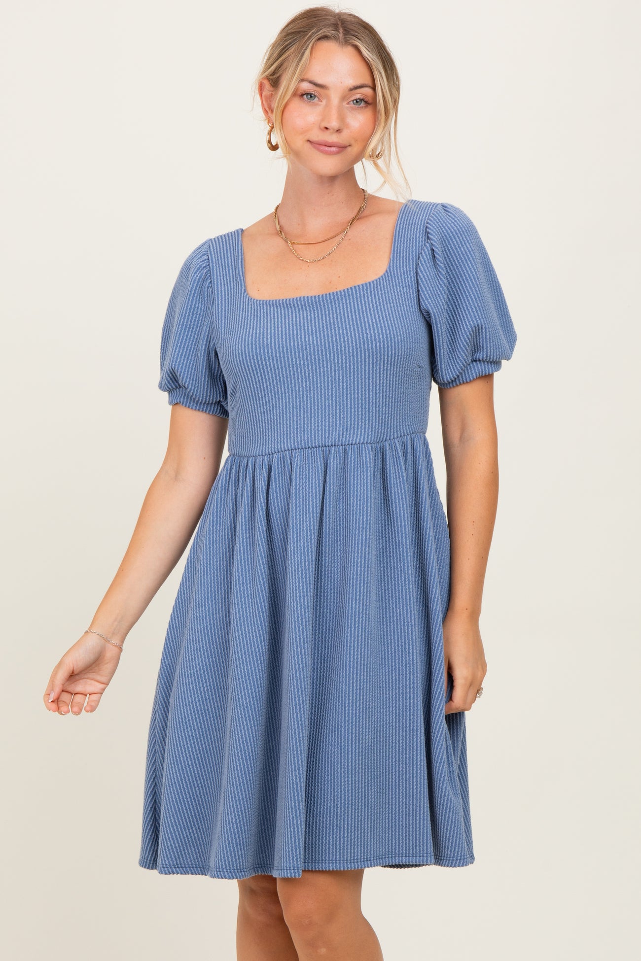 woman wearing a blue striped puff sleeve dress with a square neckline and a flared skirt