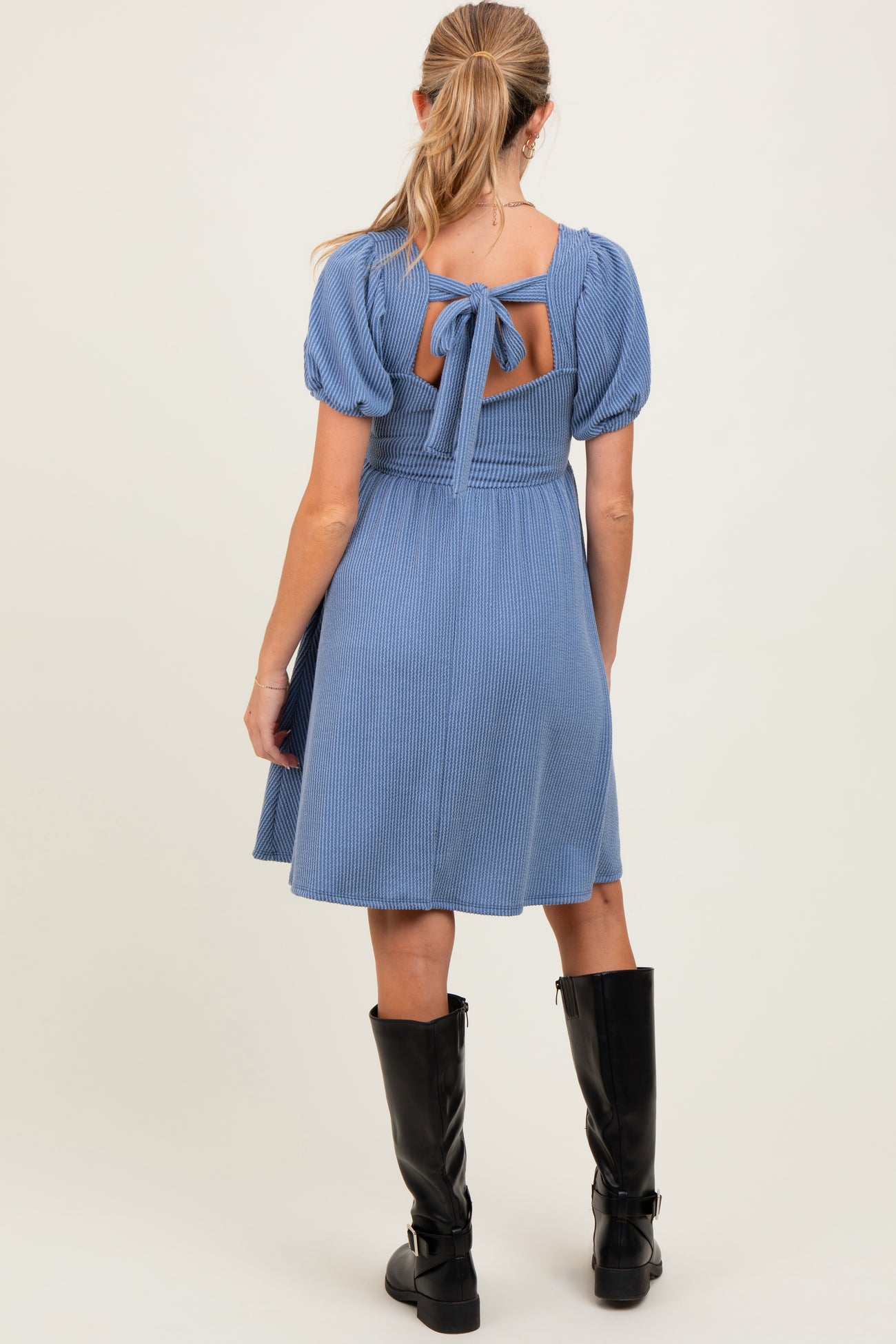 woman wearing a light blue ribbed maternity dress with puff sleeves and a back tie detail