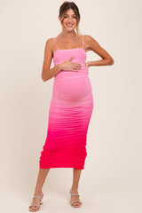 woman wearing a pink ombre maternity dress with ruching, showcasing her baby bump while standing and smiling