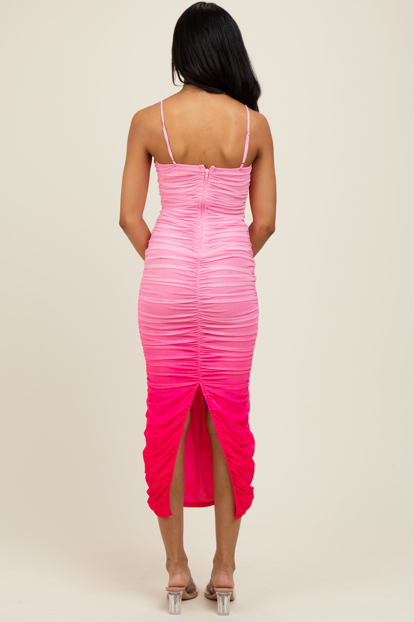 woman wearing a pink ombre fitted dress with ruching and a back slit, showing the back view