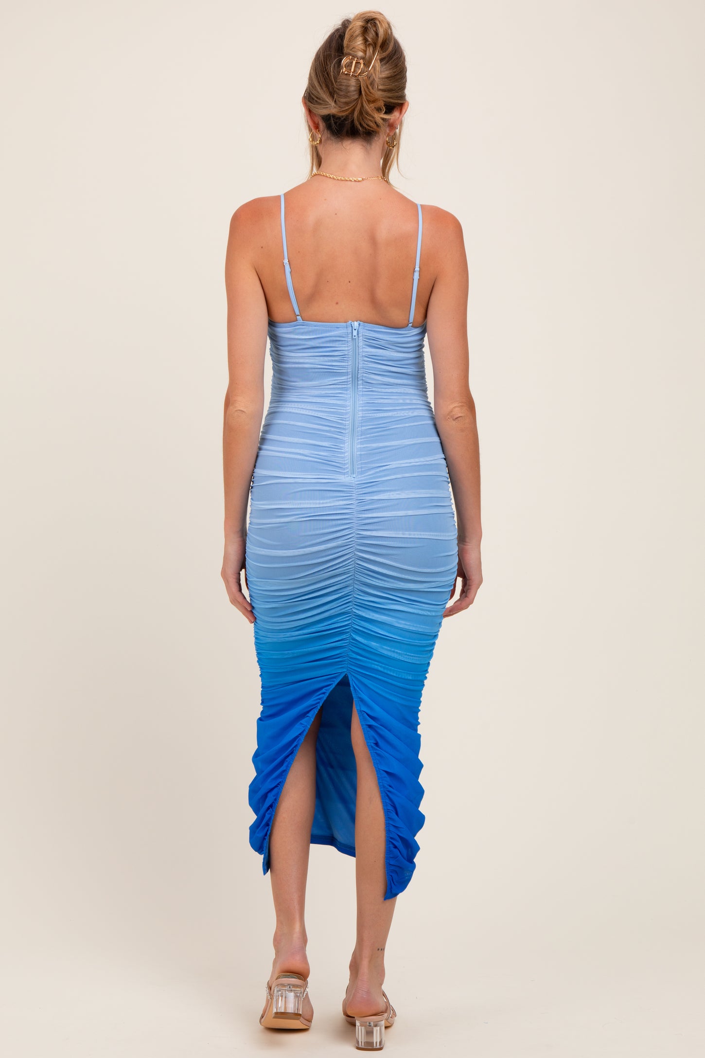 woman wearing a gradient blue maternity dress with ruching and a slit at the back