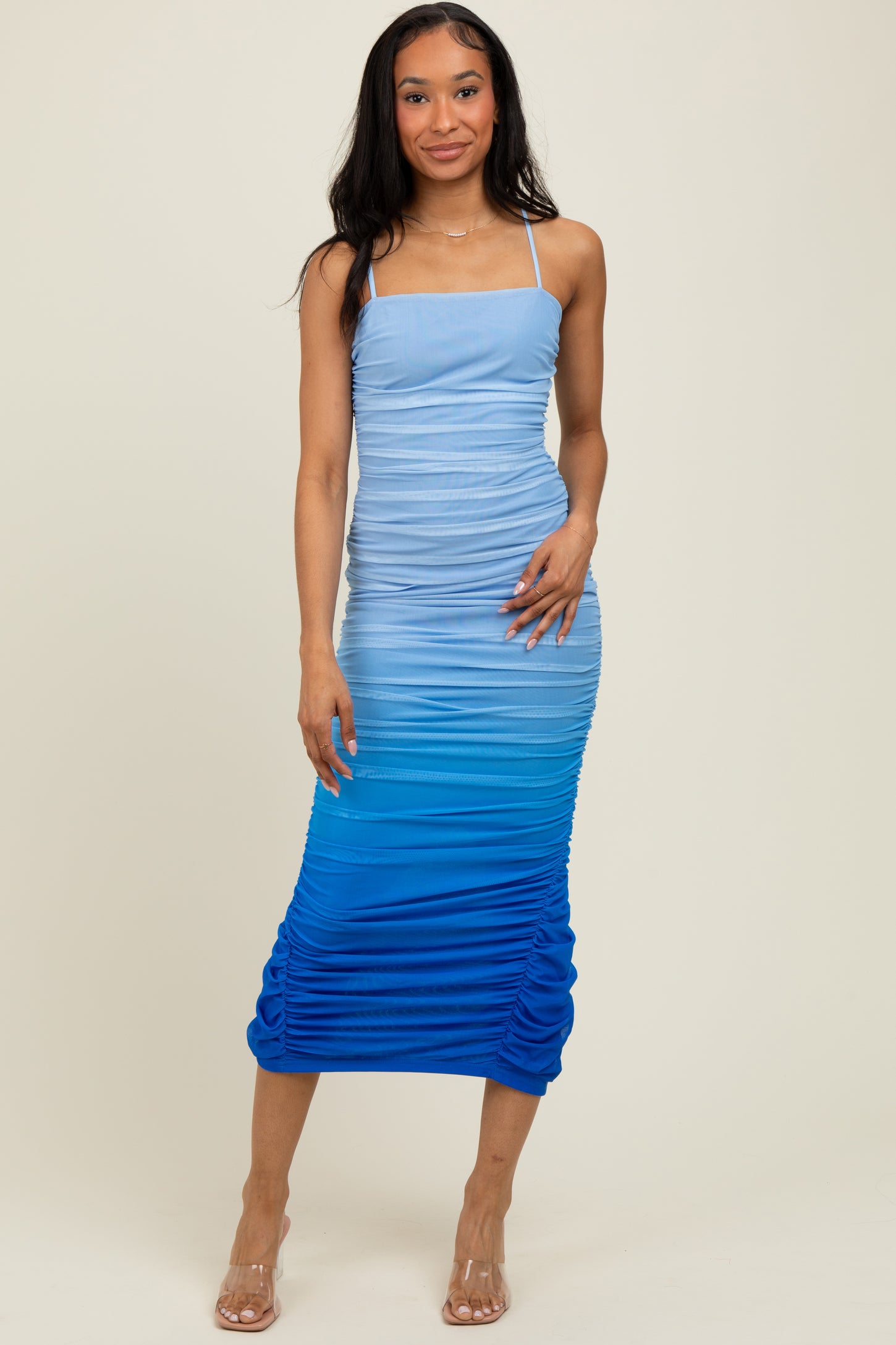 woman wearing a blue ombre ruched midi dress with adjustable spaghetti straps