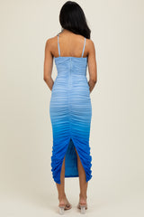woman wearing a blue ombre ruched midi dress with adjustable straps and a slit at the back