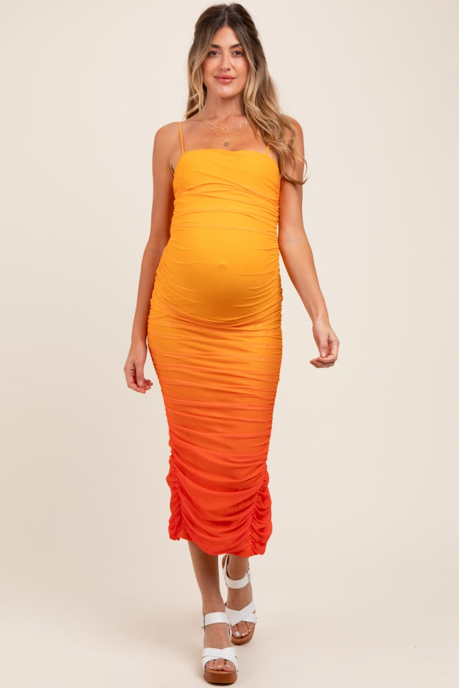 woman wearing a maternity orange ombre ruched midi dress with spaghetti straps and a visible baby bump