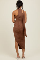 woman wearing a brown ruched midi dress with a halter neck and a flowing detail at the back