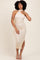 woman wearing a cream-colored sleeveless bodycon dress with draped detailing and a high neckline