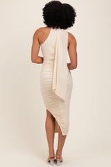 woman wearing a beige one-shoulder midi dress with ruching and a flowing drape at the back