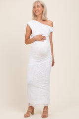 woman wearing a white one-shoulder lace maternity dress and holding her baby bump