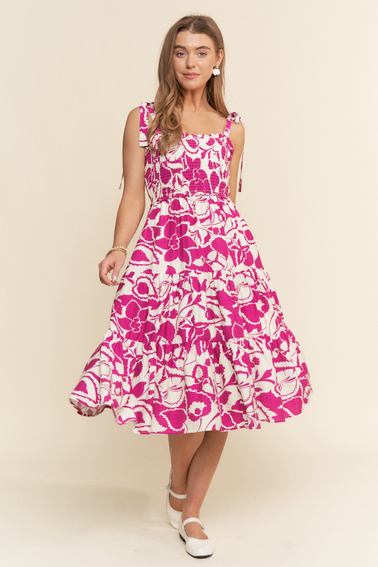 woman wearing a pink floral midi dress with tie straps and a tiered skirt
