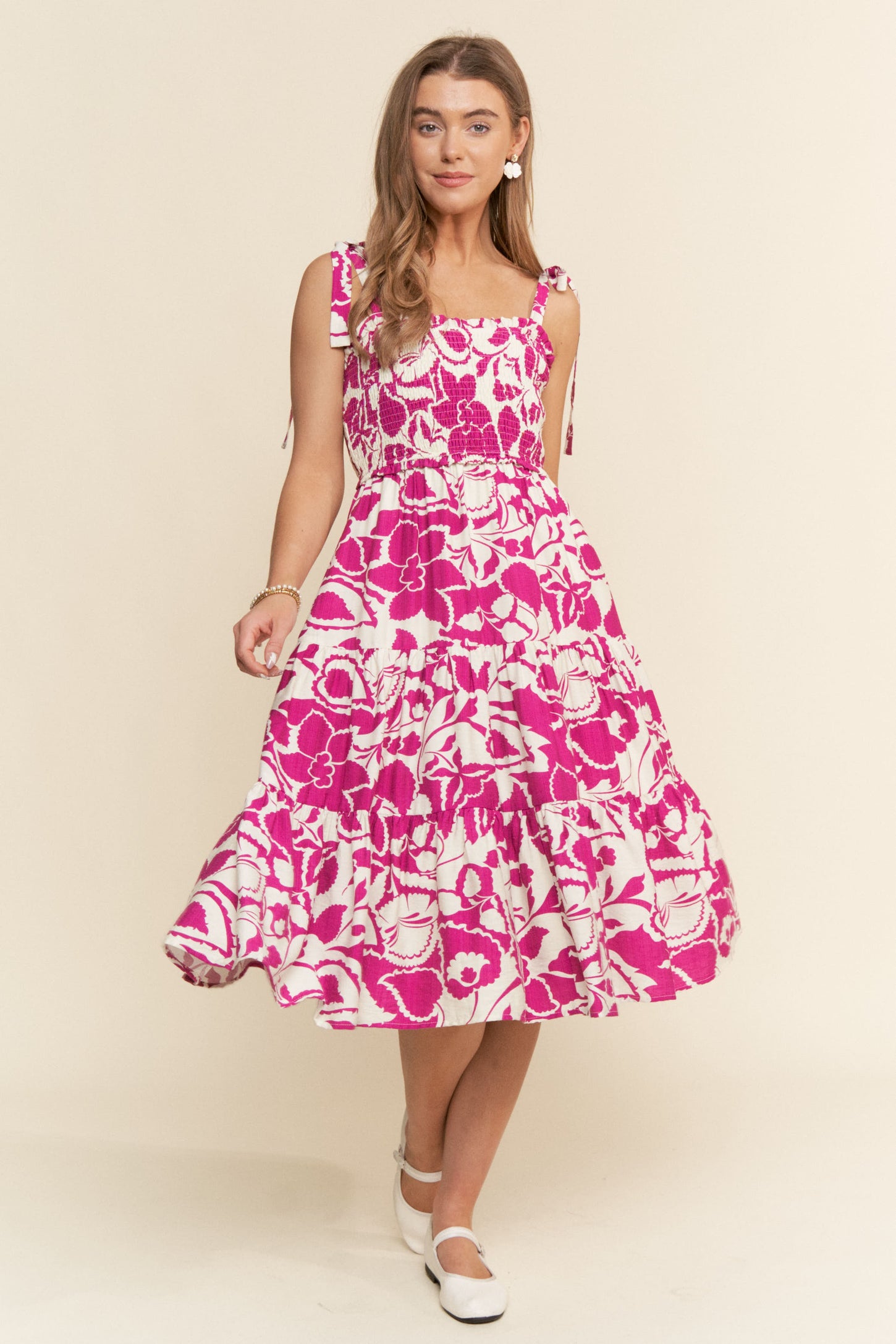woman wearing a pink floral midi dress with tie straps and a tiered skirt