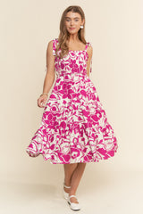 woman wearing a pink floral midi dress with tie straps and a tiered skirt