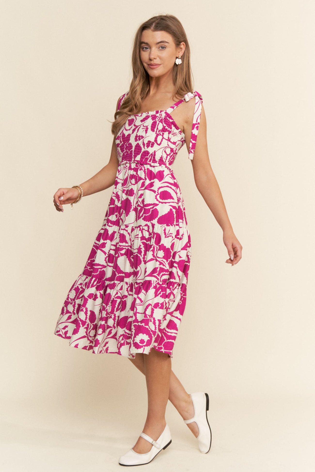 woman wearing a pink and white floral midi dress with tie straps and a fitted bodice