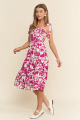 woman wearing a pink and white floral midi dress with tie straps and a fitted bodice
