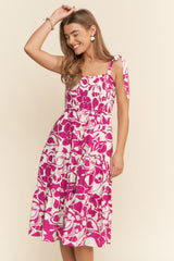 woman wearing a pink and white floral print midi dress with adjustable tie straps and a smocked bodice