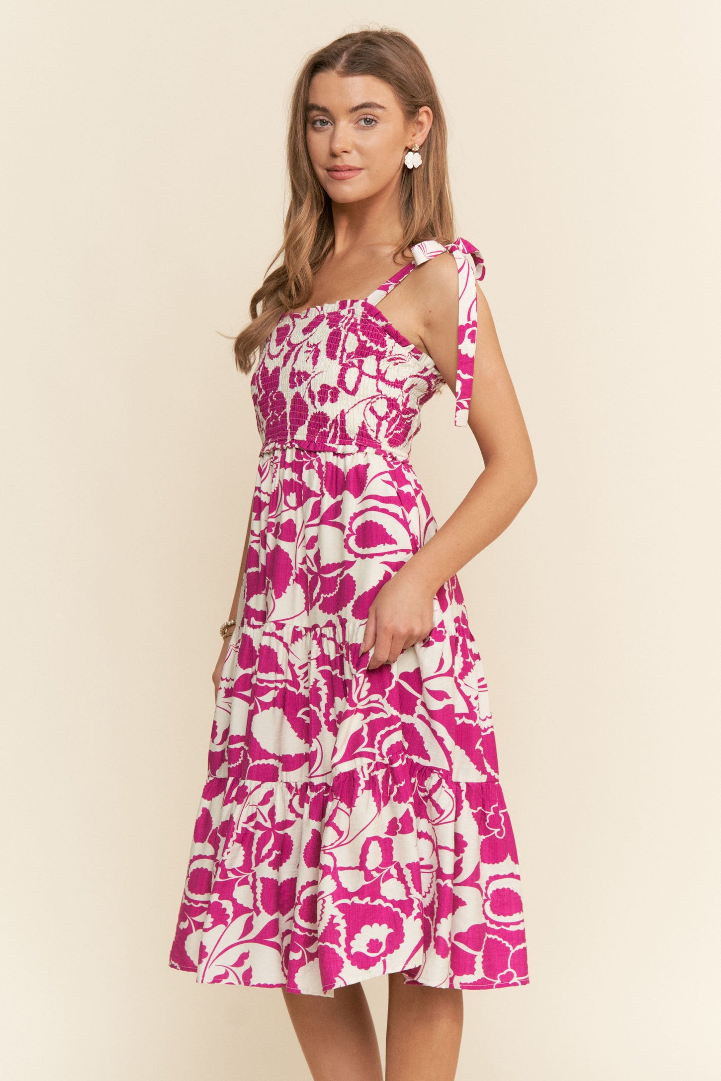 woman wearing a pink and white floral print midi dress with tie straps and a tiered skirt