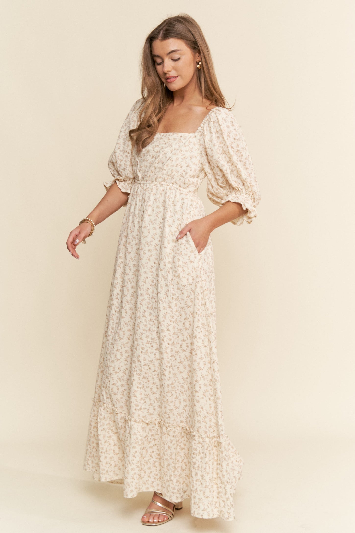 woman wearing a beige floral maxi dress with puffed sleeves and side pockets