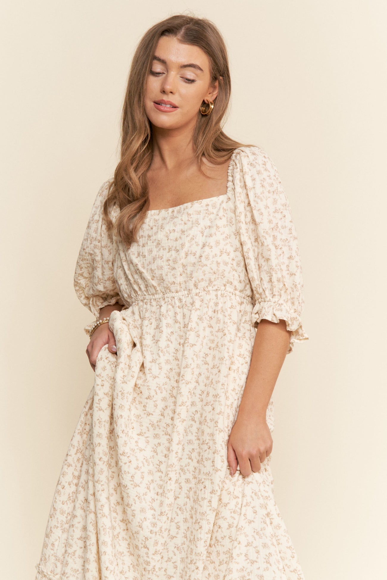 woman wearing a cream floral midi dress with puff sleeves and a square neckline
