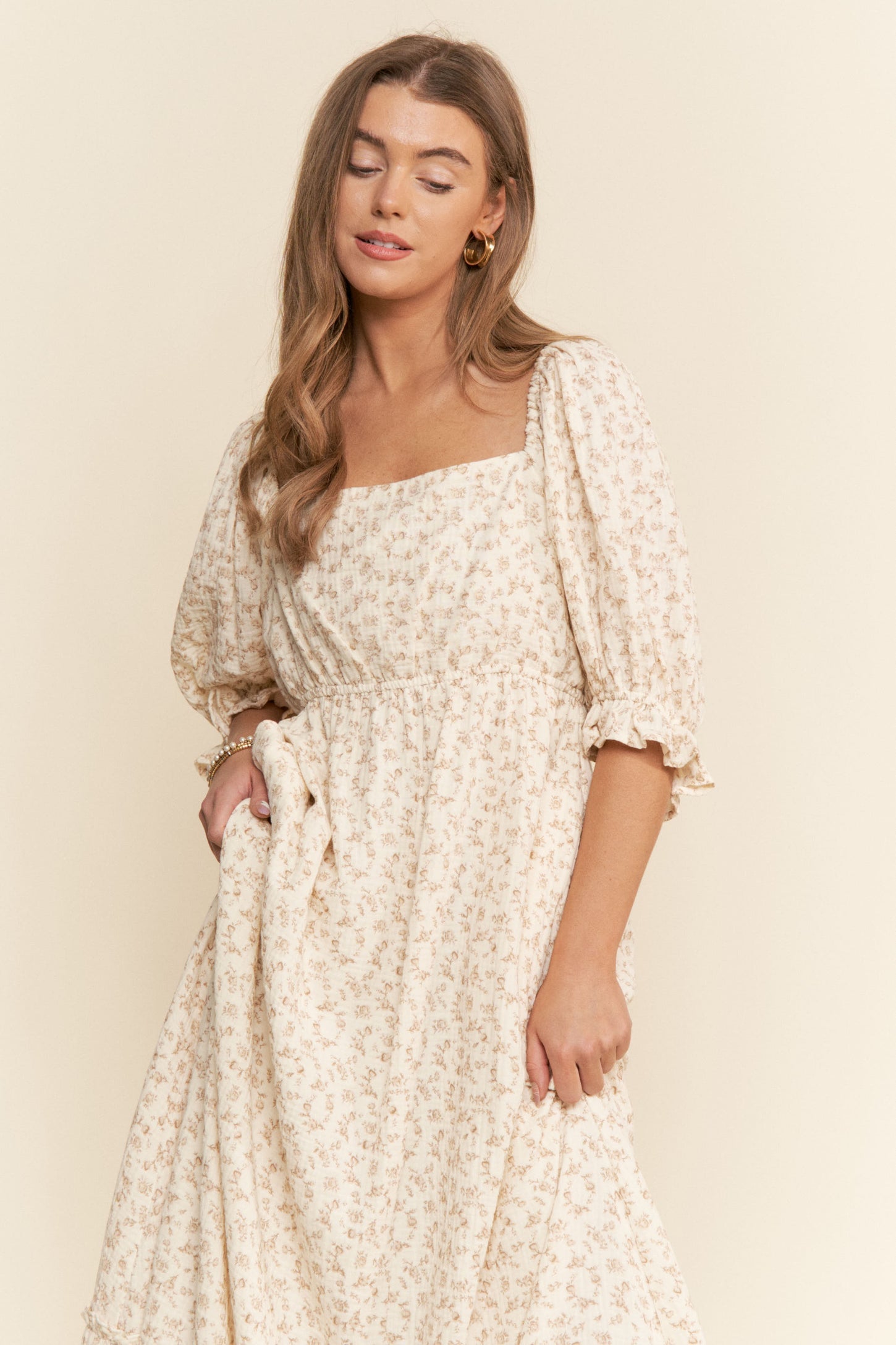 woman wearing a cream floral midi dress with puff sleeves and a square neckline