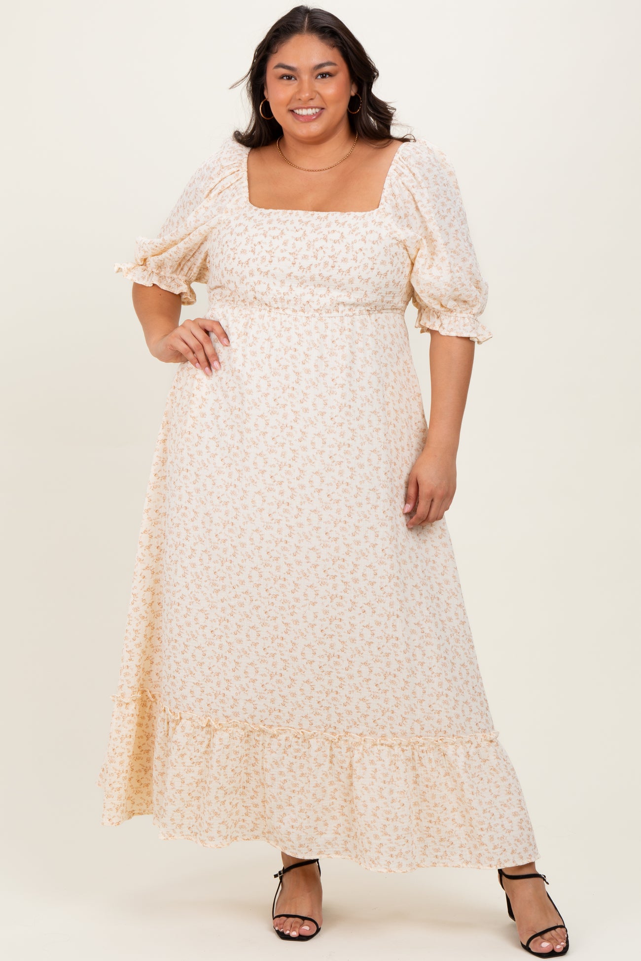 woman wearing a cream floral maxi dress with puff sleeves and a square neckline, styled with strappy black heels