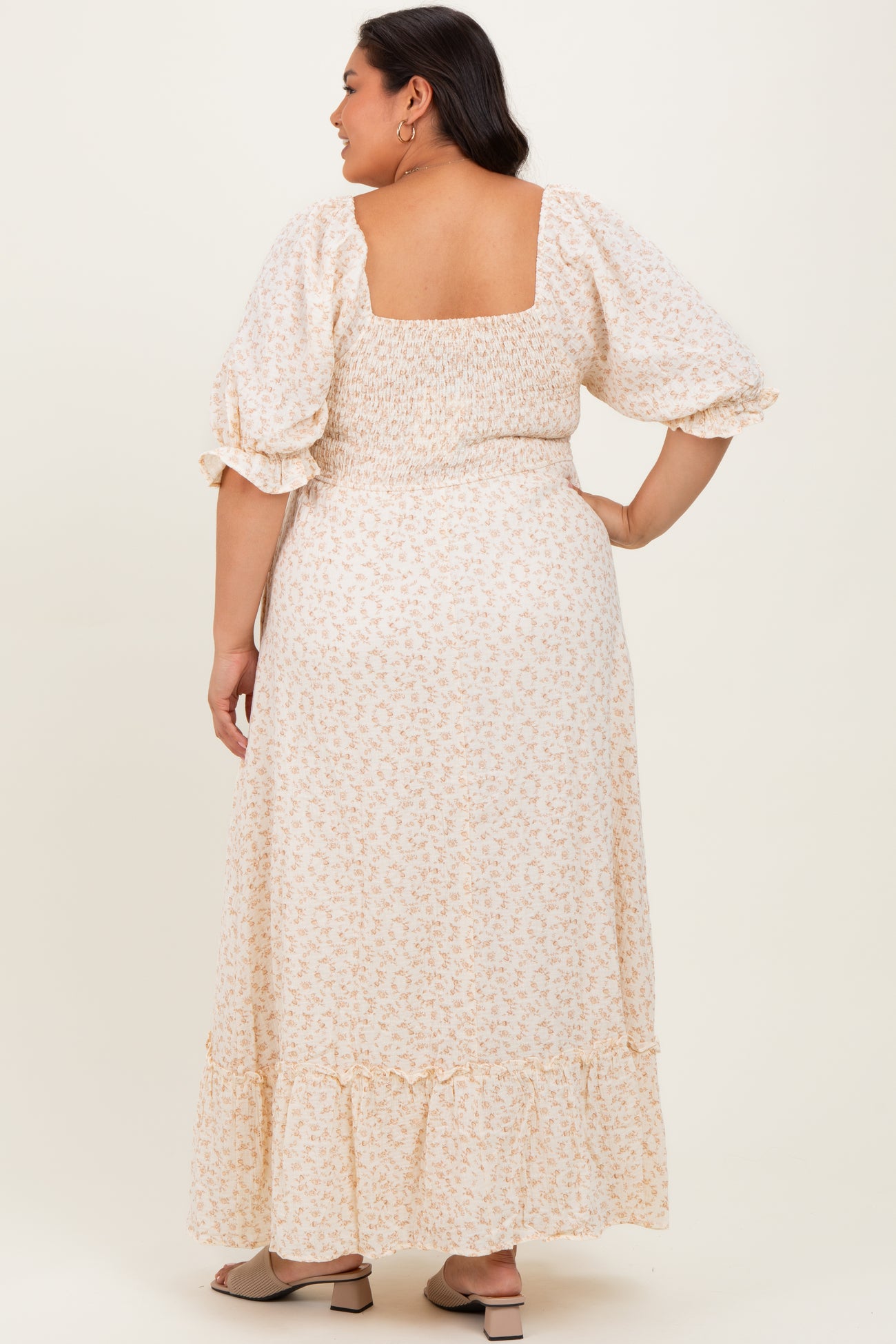 woman wearing a floral plus size maxi dress with puff sleeves and a smocked waist, shown from the back