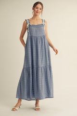 woman wearing a light blue maxi dress with adjustable shoulder straps and a tiered skirt