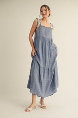 woman wearing a light blue tiered maxi dress with adjustable straps and pockets